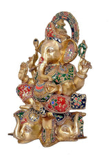 Brass Ganpati statue side view, elephant-headed four arms with colorful inlay clothing