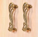 Ornate peacock brass door handle pair with oval screw plates and curved pull
