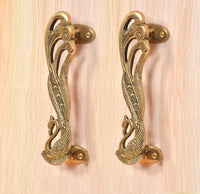 Ornate peacock brass door handle pair with oval screw plates and curved pull