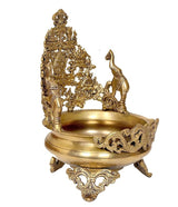 Brass urli bowl with ornate deity stand, turned bowl, and carved feet; side angle