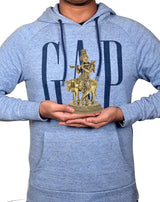 Brass Krishna statue on cow, held by person for size, flute and crown visible
