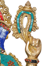 Close-up of Ganesha hand and gold arm holding a teal-and-gold decorative element