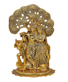 Goldenes Radha-Krishna-Metallidol frontal: zwei Figuren mit Kuh, auf Ornament-Boden