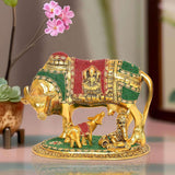 Gold metal cow idol with calf and Bal Krishna, red and green jeweled decorations