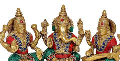 Brass Lakshmi Ganesh Saraswati statue close-up: gold faces with red eyes, raised hands