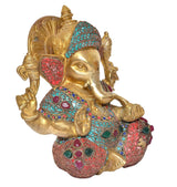 Ganesha idol angled view, golden face with turquoise-and-red decorative jewelry