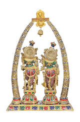 Close view: Radha and Krishna under brass arch with fan-like discs and bell