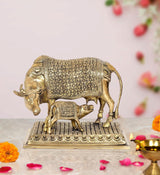 Brass cow with calf showpiece, ornate floral engraving, curved horns, on textured base