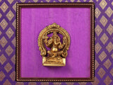 Golden Ganesha idol in inner beaded frame on purple fabric background