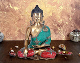 Brass Buddha statue sitting cross-legged with turquoise draped shawl and red detailing