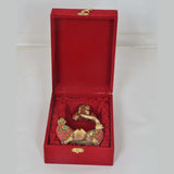 Open red gift box with a gold elephant figurine and jeweled ornament on red padding