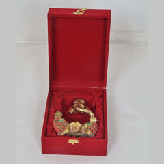 Open red gift box with a gold elephant figurine and jeweled ornament on red padding