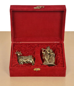 Open red velvet gift box with brass cow calf and Radha Krishna statues
