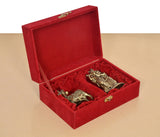Red velvet gift box open showing brass Radha Krishna statue and cow calf