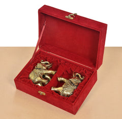Open red velvet gift box with two brass elephant figurines