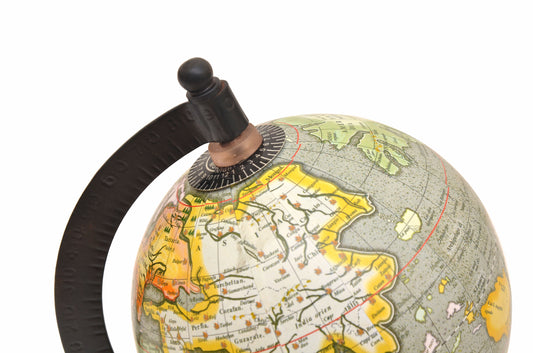 Magnifying-glass desktop globe view: Latin-style map, grey oceans, colorful land, black arm