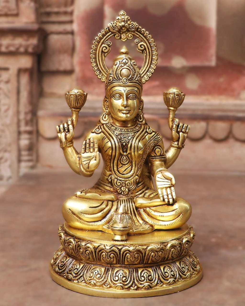 Brass Lakshmi idol with crown and circular halo, seated with four raised hands
