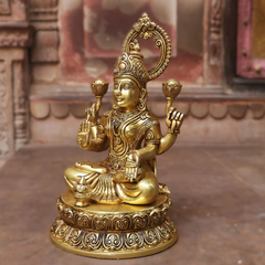Seated brass Lakshmi idol facing right, four-armed pose with decorative jewelry