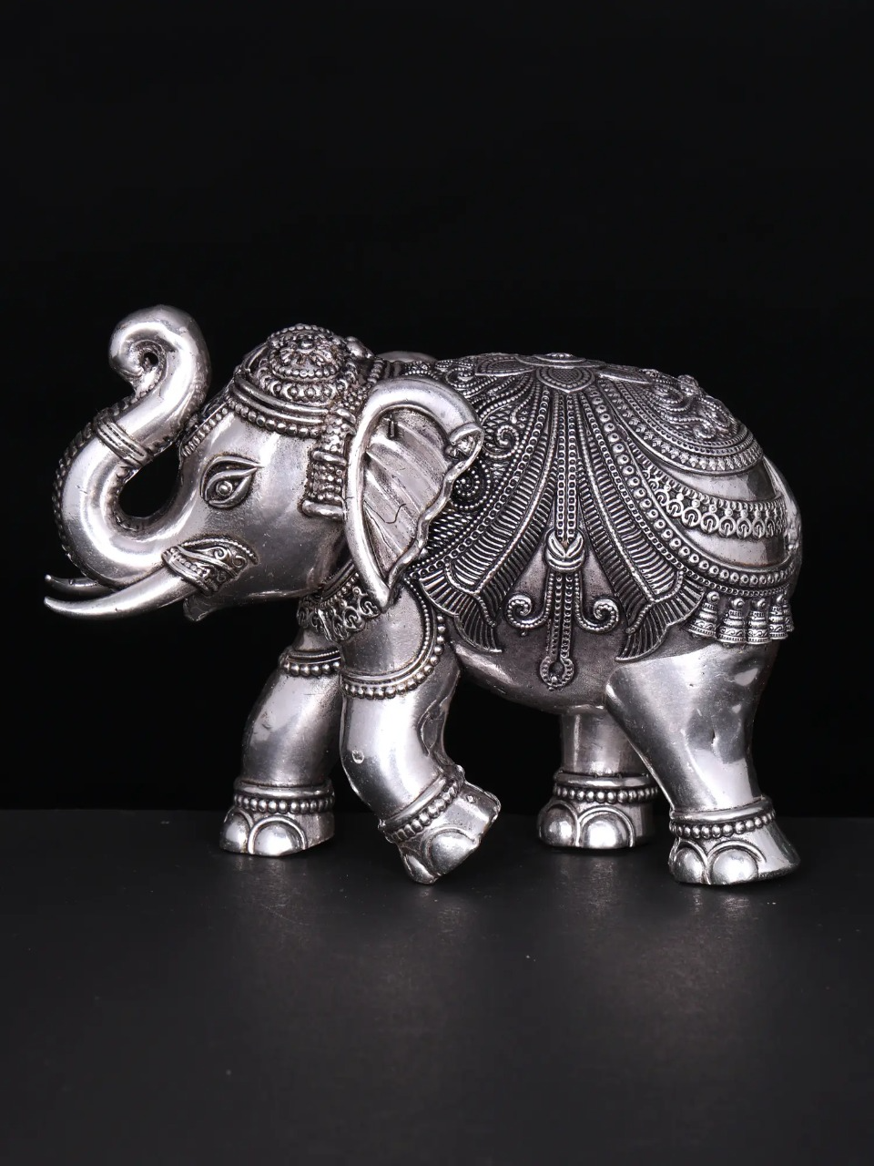 Silver brass elephant figurine with detailed engraved patterns, side view