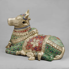 Seated Nandi sculpture close-up: gold-toned face and decorated floral stonework armor