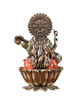Saraswati brass idol back view with ornate crown; red-green accents on lotus base
