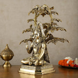 Brass Lord Shiva statue under tree canopy, seated figure with many small birds and trident