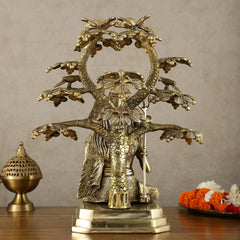 Brass Lord Shiva statue under tree, pedestal base with serpent trunk and raised trident