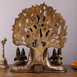 Back view of large brass Dakshinamurthy statue with carved tree-like halo and base