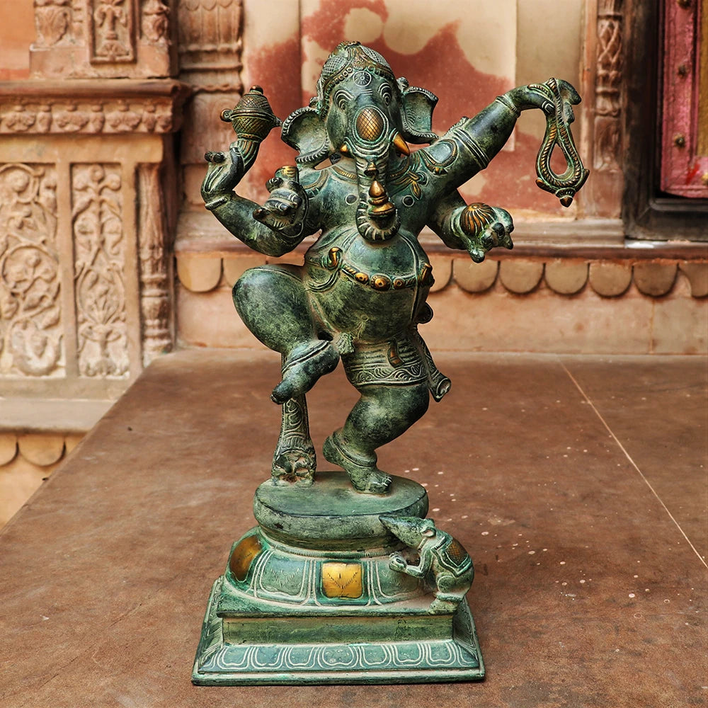 AONA brass dancing Ganesha idol with raised arms, ornate patina finish on pedestal base