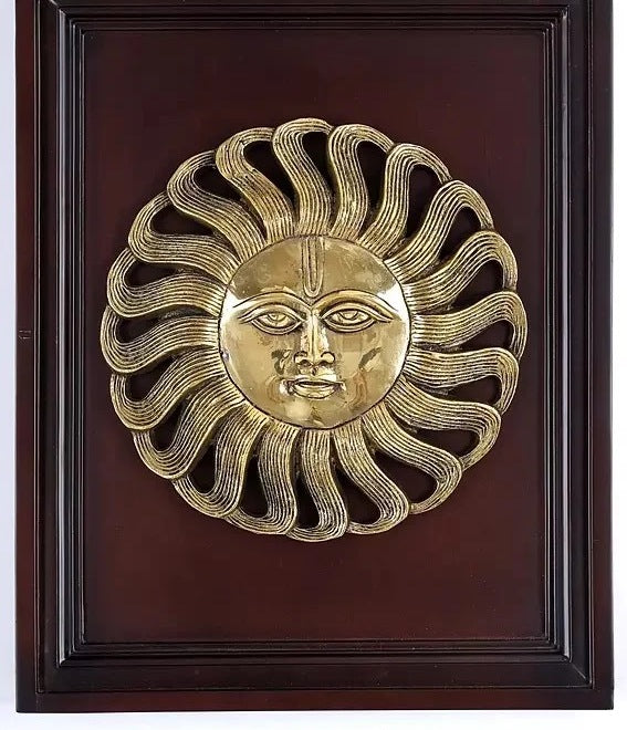 Brass Surya wall statue in dark wood frame, gold sun-face relief, serene expression
