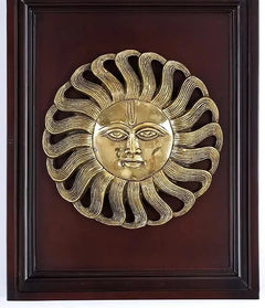 Brass Surya wall statue in dark wood frame, gold sun-face relief, serene expression
