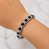 Silver link bracelet on wrist with dark round beads and textured rectangular links