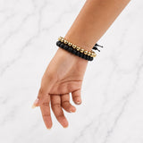 Black beaded bracelet with gold-tone bead accents and dangling tassels on wrist