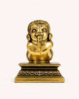 Brass Baby Ganesha figurine with face detail, seated meditation pose on ornate pedestal