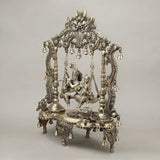 Brass Radha-Krishna jhula: detailed pillars, floral base, and hanging bell chains