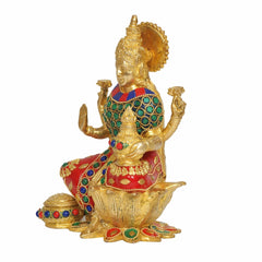 Brass Lakshmi statue side view, ornate crown, jeweled green-and-red outfit on lotus base