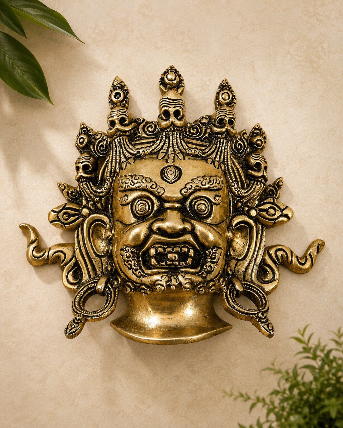 Brass Mahakaal Jambala face wall hanging, ornate gold deity mask with curled ornaments