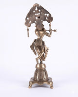Brass Krishna idol rear view, halo-like arch, hanging ornaments, carved lower base