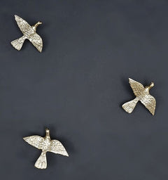 Gold-toned butterfly ornaments for wall hanging, three winged figurines on a dark plate