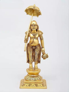 Brass Dashavatara figure holding a large disc-like weapon on a tall staff, halo above.