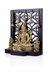 Brass Shiva idol with standing figures, filigree backdrop, hanging bells, on dark base