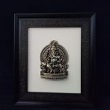 Ganesha-Relief im Rahmen: sitzende Figur mit goldfarbenem Detail und ornamentalem Rückenrahmen