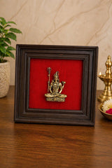 Framed brass Lord Shiva idol with red backing in a dark wooden frame