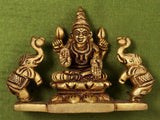 Brass Gajalakshmi idol close-up in wooden frame, flanked by two side figures