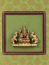 Framed brass Gajalakshmi idol with four arms and headgear, centered display