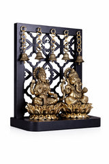 Brass Ganesha and Lakshmi idol with hanging bells on ornate lattice panel