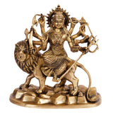 Brass Durga idol seated on lion, ornate crown and jewelry, arms raised with weapons