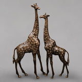 Antique copper brass giraffe figurines, two standing together with textured spots