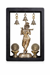 Brass Lord Krishna idol in frame with three hanging bells and two decorative oil lamps