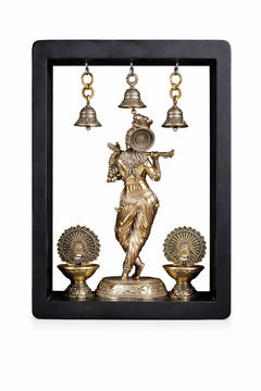 Brass Lord Krishna idol in frame with three hanging bells and two decorative oil lamps